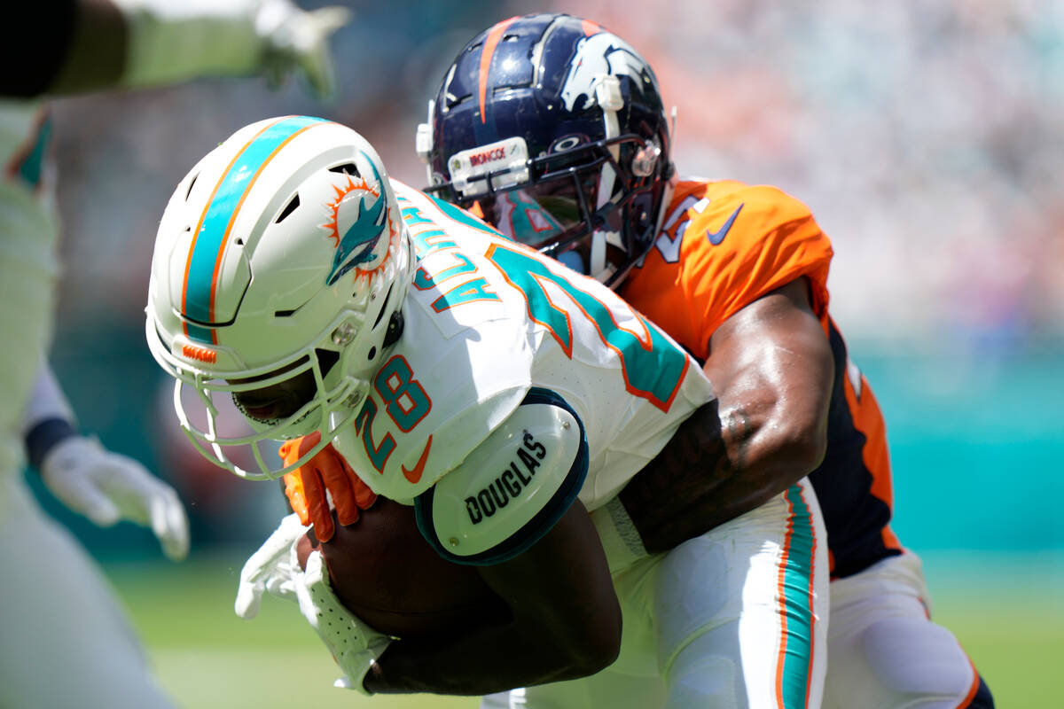 Denver Broncos cornerback Damarri Mathis (27) tackles Miami Dolphins running back De'Von Achane ...