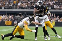 Las Vegas Raiders wide receiver Davante Adams, center, makes a catch as he is tackled by Pittsb ...