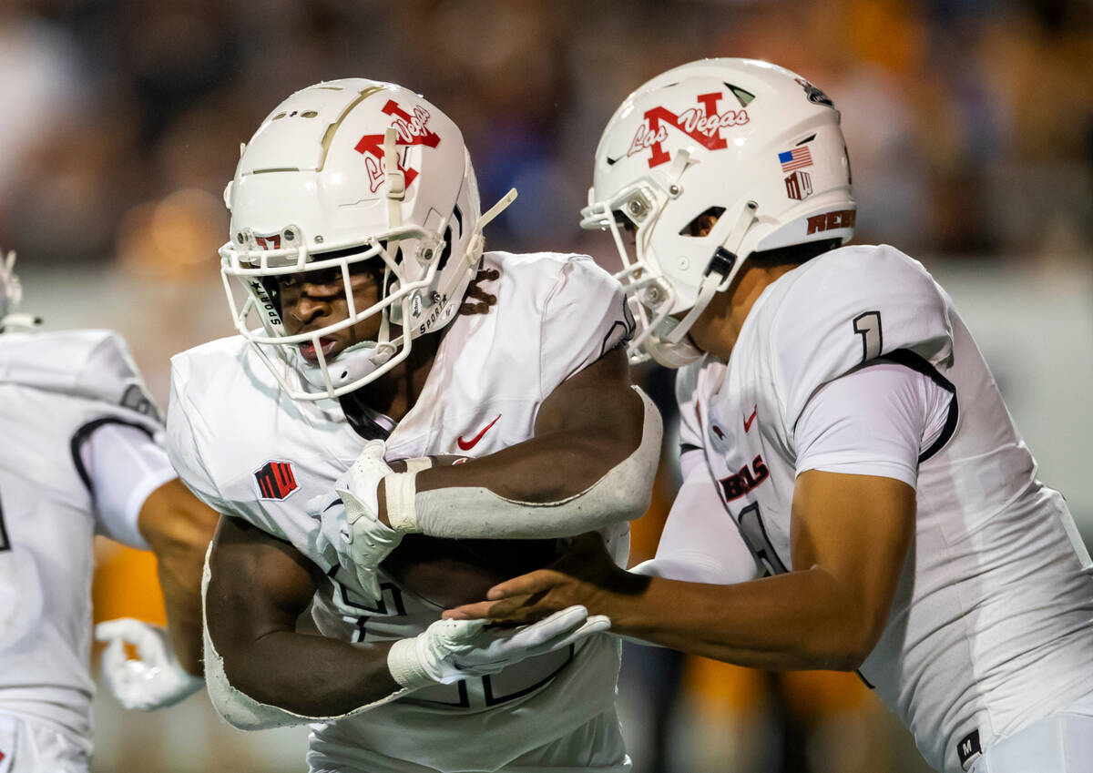 UNLV running back Jai'Den Thomas, left, takes a handoff from quarterback Jayden Maiava during t ...