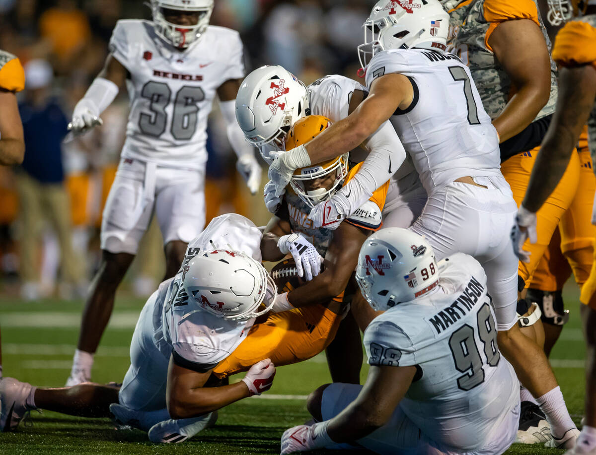 UTEP running back Torrance Burgess Jr., center, is sacked by UNLV defensive end Elijah Shelton, ...
