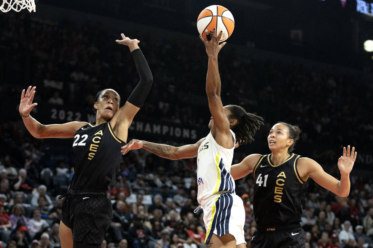 Dallas Wings guard Crystal Dangerfield, center, shoots against Las Vegas Aces forward A'ja Wils ...