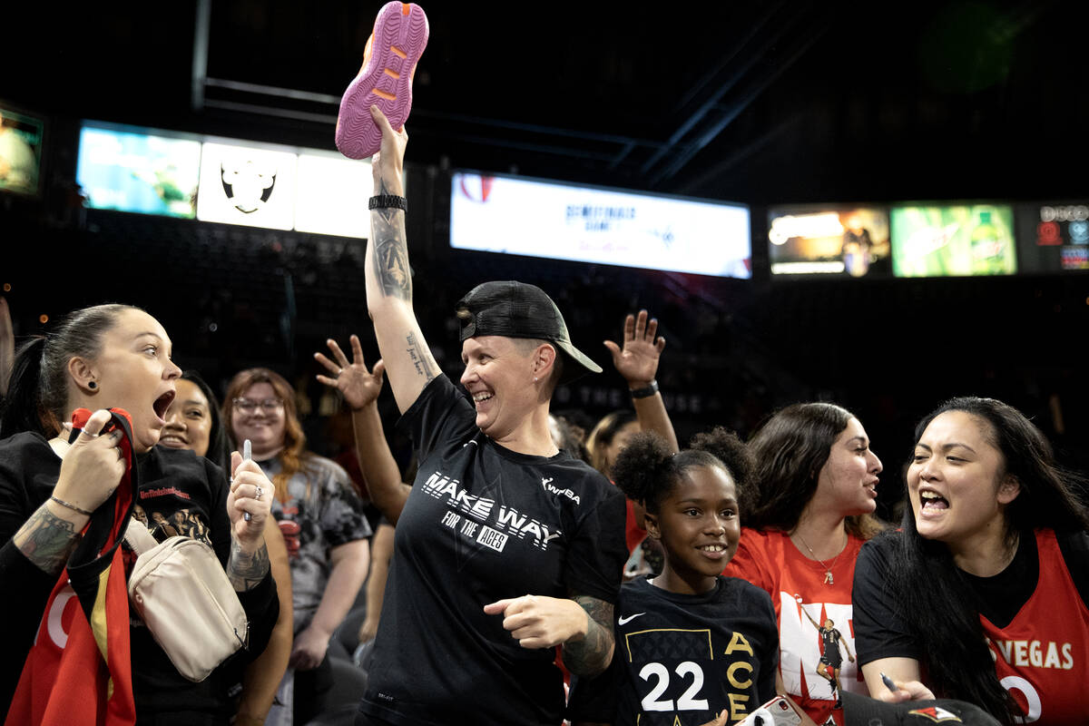 A fan celebrates after catching a signed shoe after the Las Vegas Aces won Game 1 of a WNBA bas ...