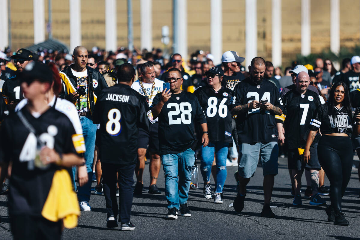 Fans walk across Mandalay Bay Drive to attend a Raiders game against the Steelers at Allegiant ...