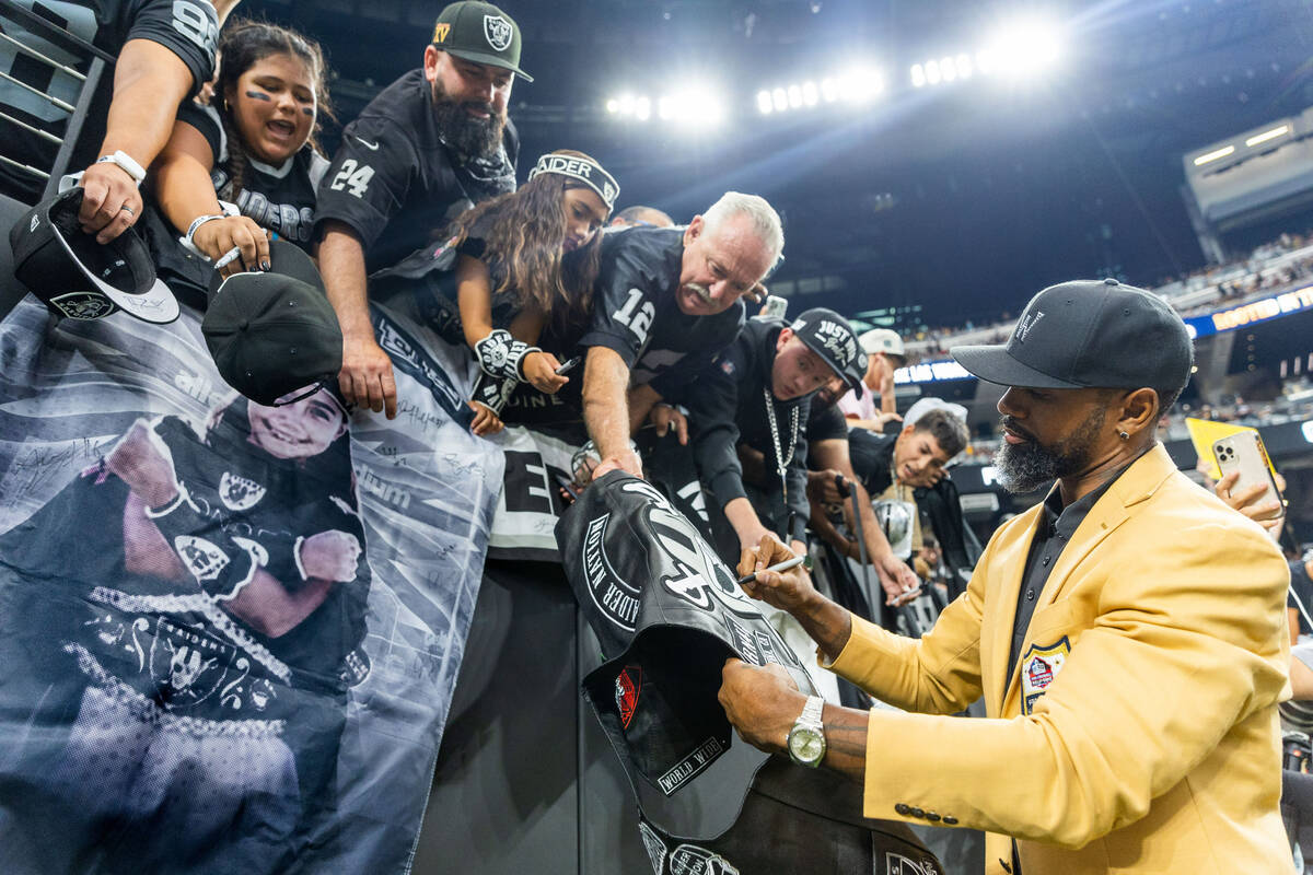 Former Raider Charles Woodson signs autographs for fans during warm ups before the first half o ...