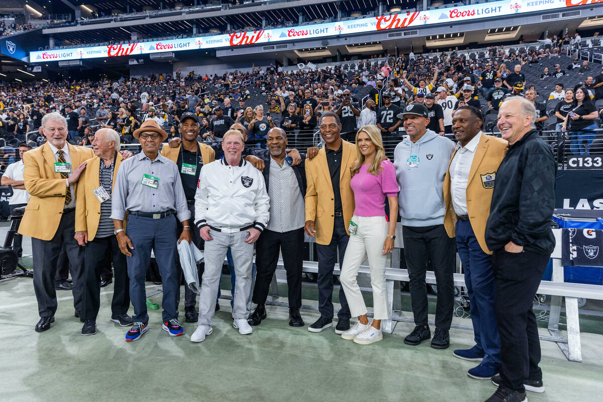 Raiders owner Mark Davis is joined by fighter Mike Tyson, alumni and others on the field during ...