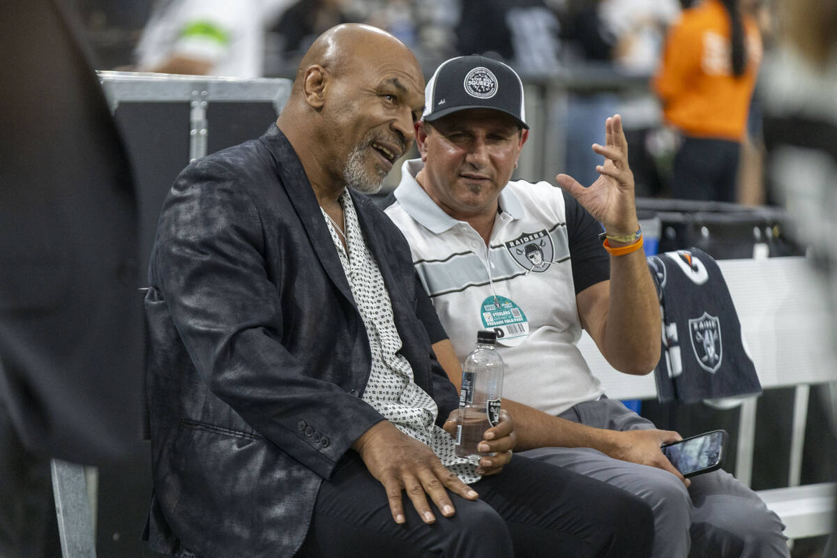 Former boxing heavyweight champion Mike Tyson, left, watches team warm ups from the sideline be ...