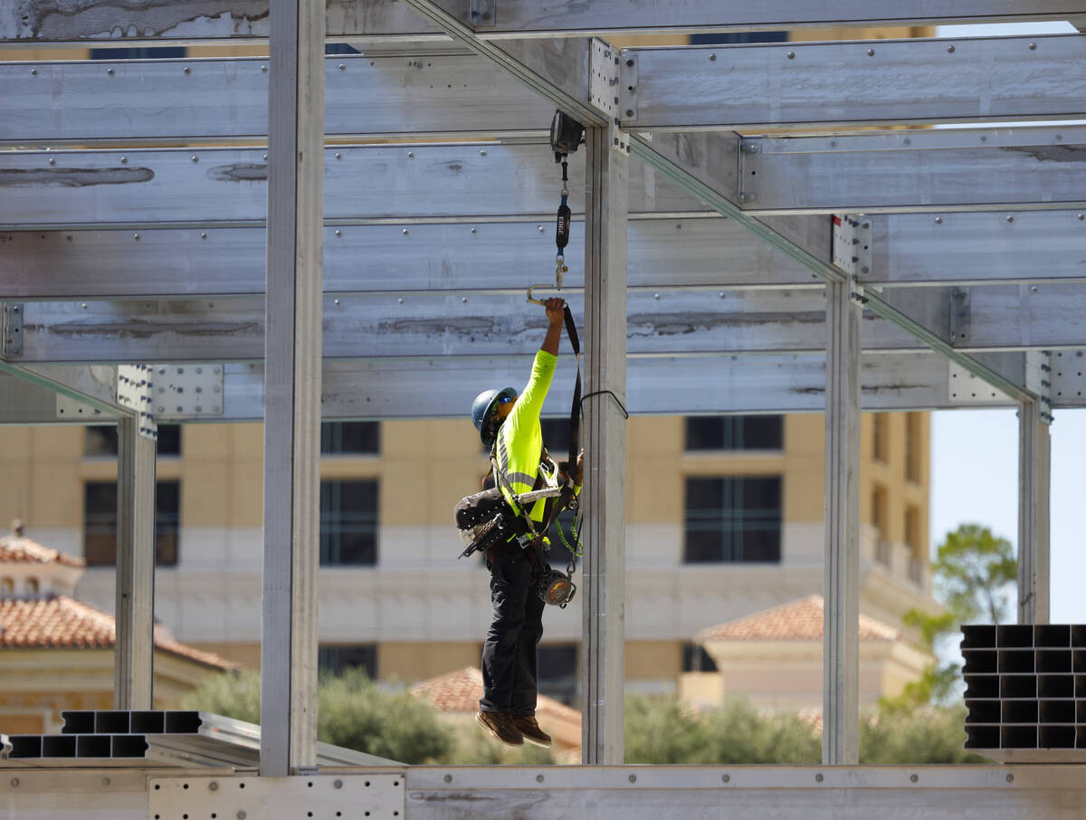 A construction worker jumps to secure his safety harness at the Formula 1 construction site at ...