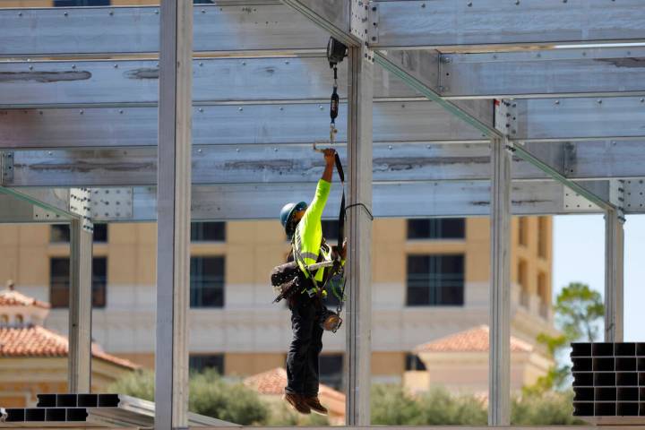 A construction worker jumps to secure his safety harness at the Formula 1 construction site at ...