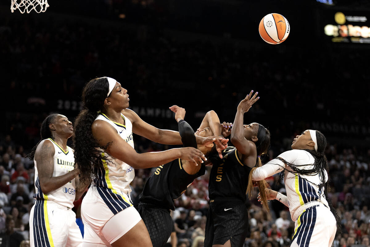 Las Vegas Aces forward A'ja Wilson, center, is fouled by Dallas Wings center Teaira McCowan (7) ...