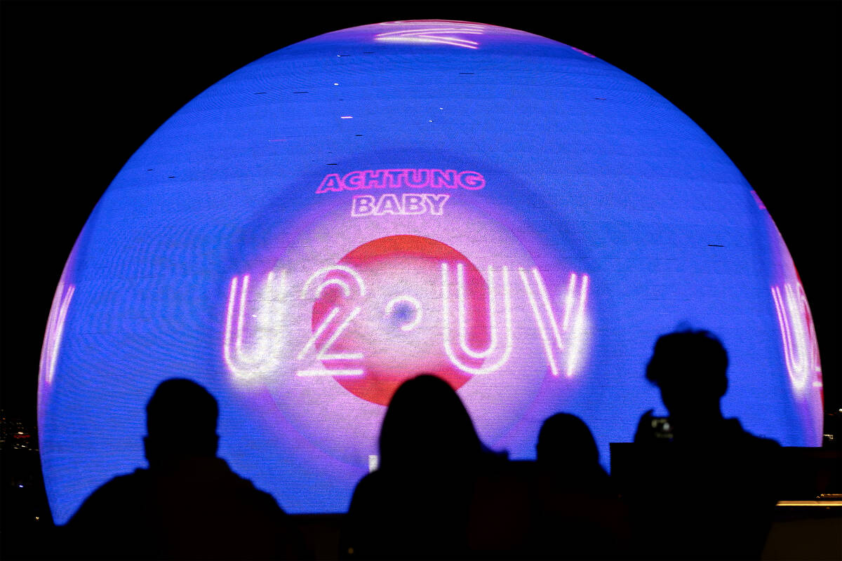 Spectators photograph The Sphere while it shows an advertisement for its opening show, U2, as s ...