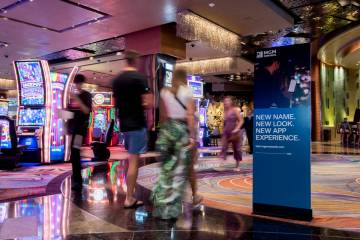 People walk past signs advertising MGM Rewards perks at the Aria hotel-casino on Friday, June 1 ...