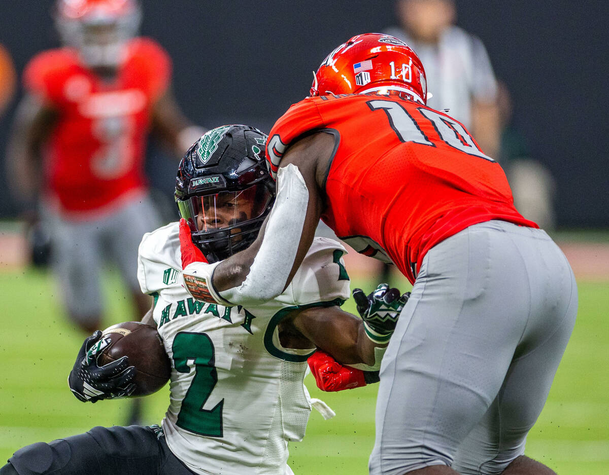 Hawaii running back Tylan Hines (2) is collared by UNLV linebacker Fred Thompkins (10) during t ...