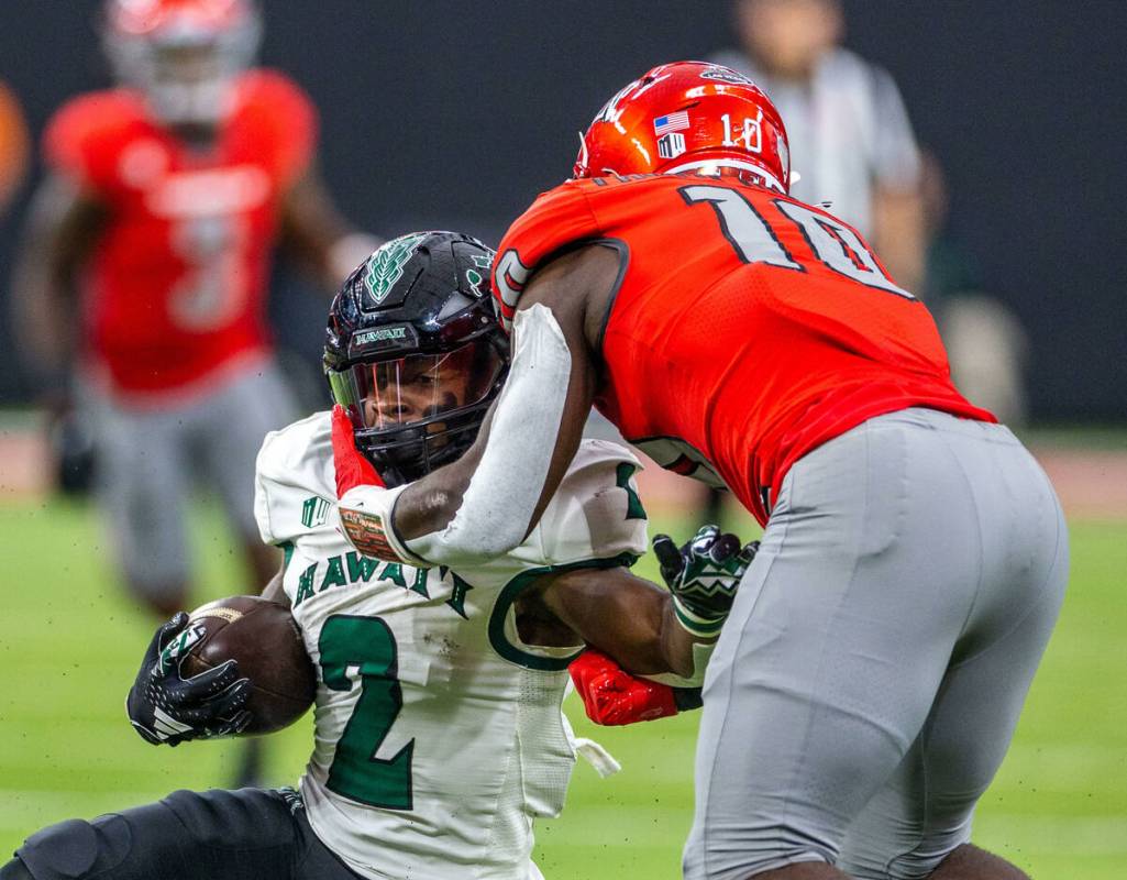 Hawaii running back Tylan Hines (2) is collared by UNLV linebacker Fred Thompkins (10) during t ...