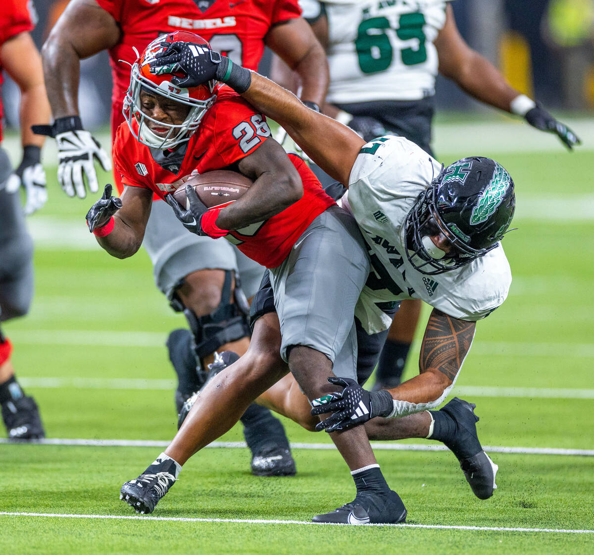 UNLV running back Courtney Reese (26) fights through a tackle attempt by Hawaii linebacker Isai ...