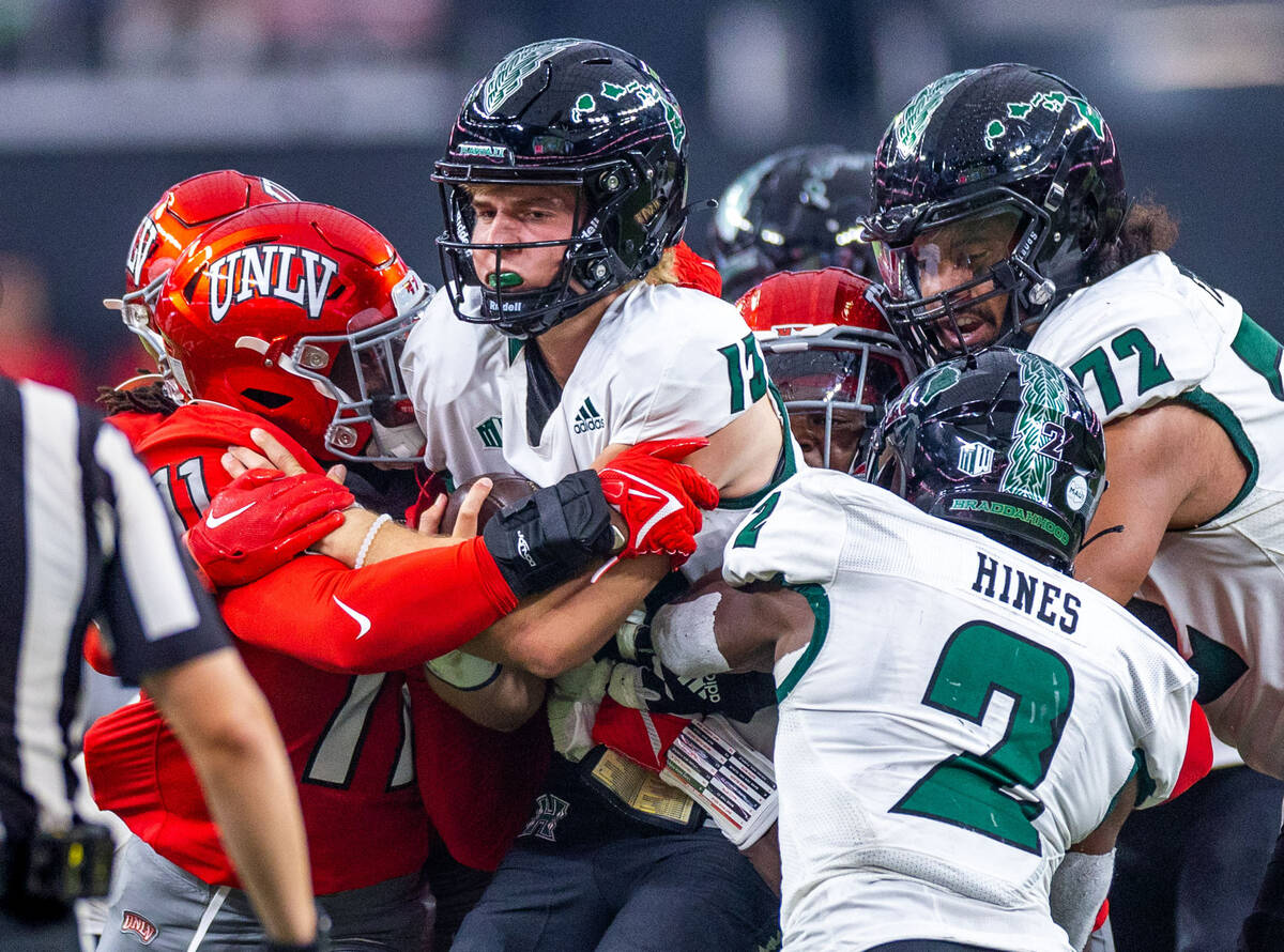 Hawaii quarterback Brayden Schager (13) is wrapped up again on another sack by UNLV linebacker ...