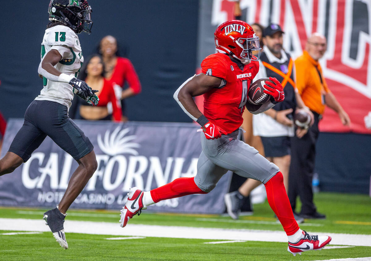 UNLV running back Donavyn Lester (4) scores a touchdown past Hawaii defensive back Caleb Brown ...