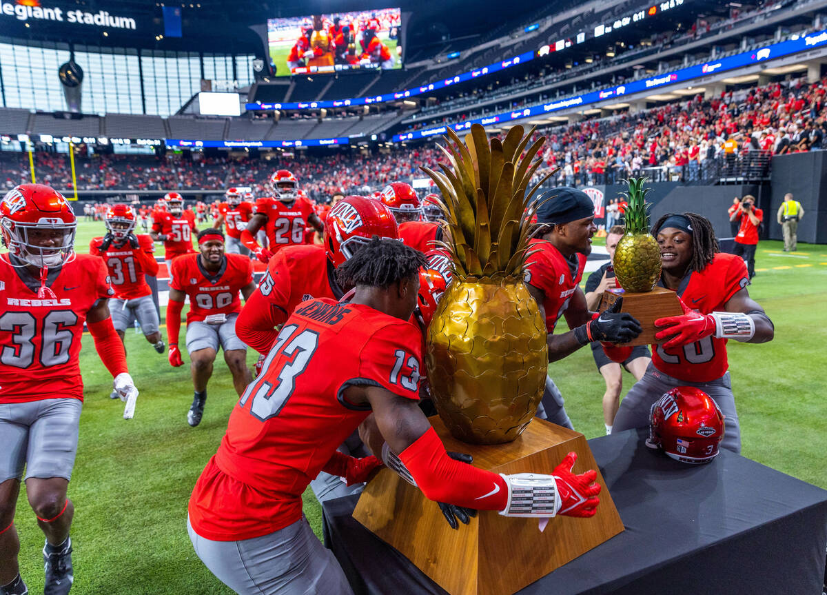 UNLV players swarm about the trophies after defeating Hawaii in the Ninth Island Showdown follo ...