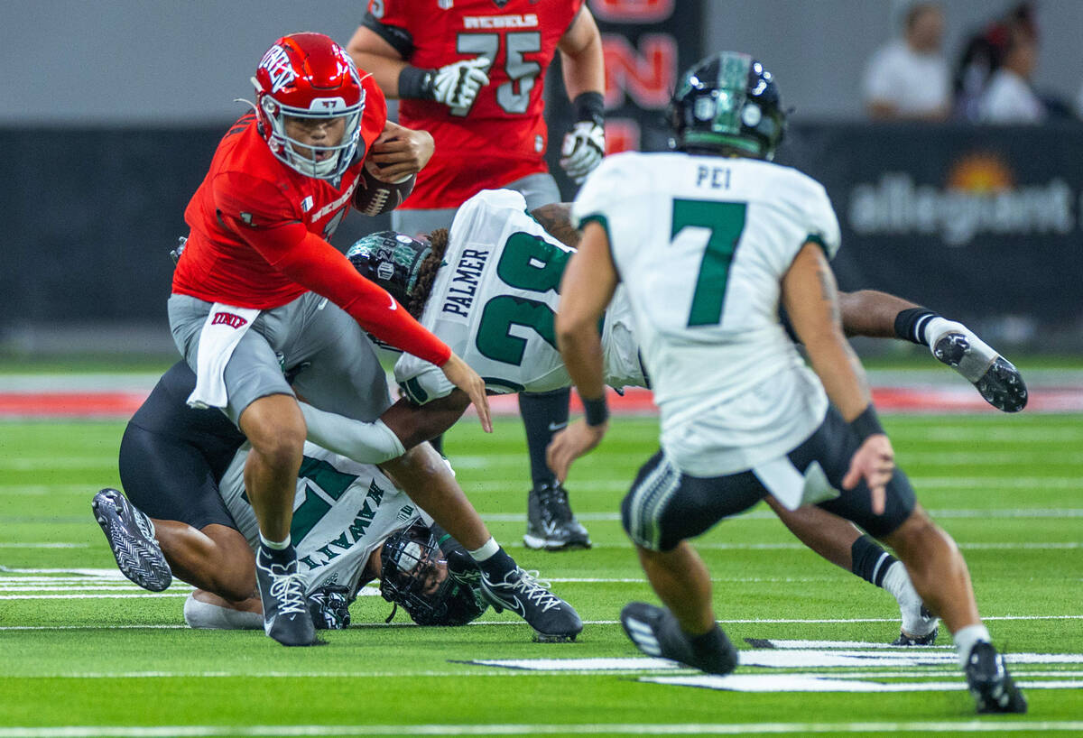 UNLV quarterback Jayden Maiava (1) is grabbed by Hawaii defensive back Elijah Palmer (28) durin ...