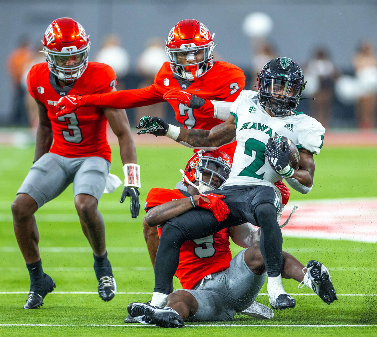 Hawaii running back Tylan Hines (2) is stopped by UNLV defensive back Jett Elad (9) during the ...