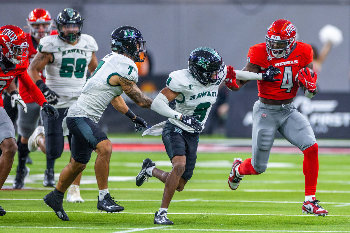 UNLV running back Donavyn Lester (4) fights for yards against Hawaii defensive back JoJo Forest ...