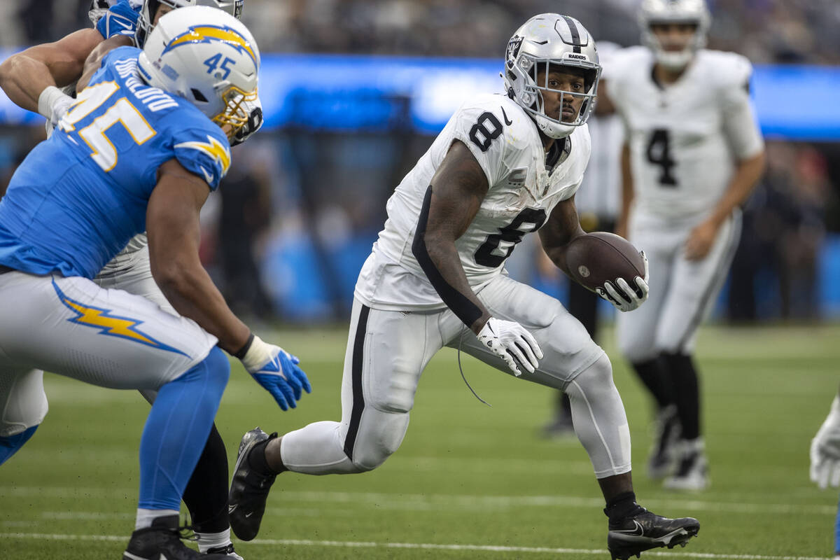 Raiders running back Josh Jacobs (8) looks for room to run as Los Angeles Chargers linebacker T ...