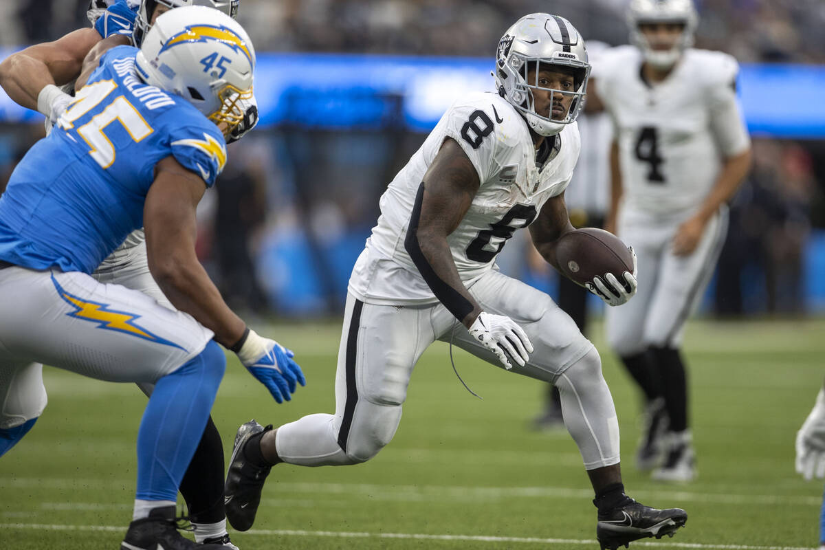 Raiders running back Josh Jacobs (8) looks for room to run as Los Angeles Chargers linebacker T ...