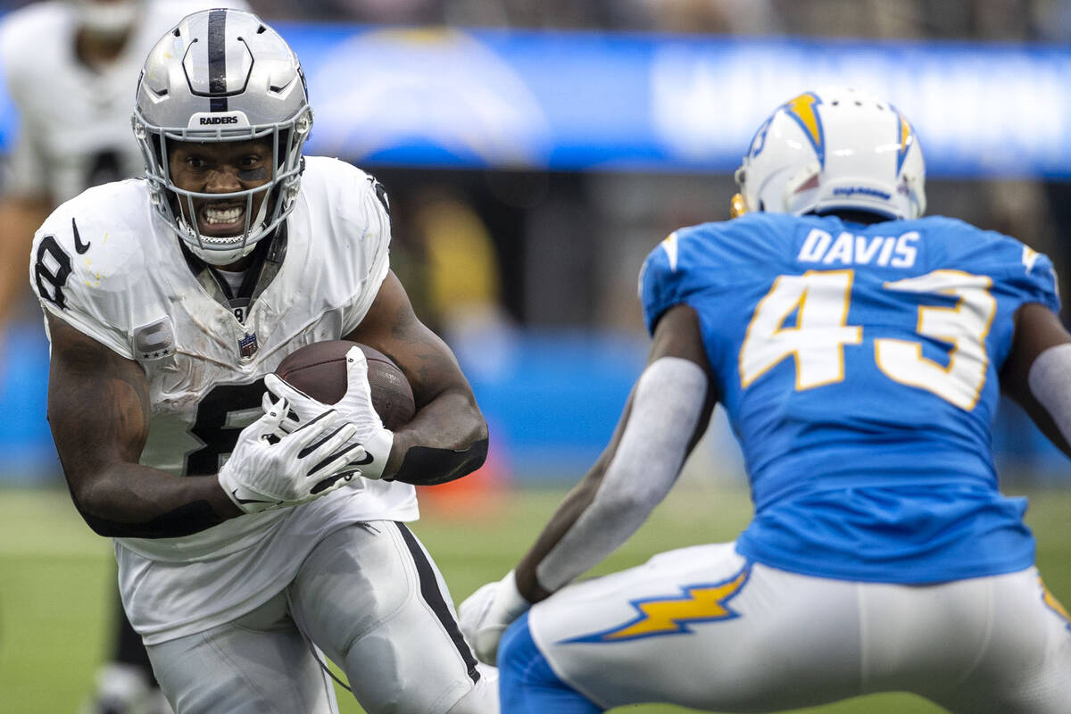 Raiders running back Josh Jacobs (8) looks to run past Los Angeles Chargers cornerback Michael ...
