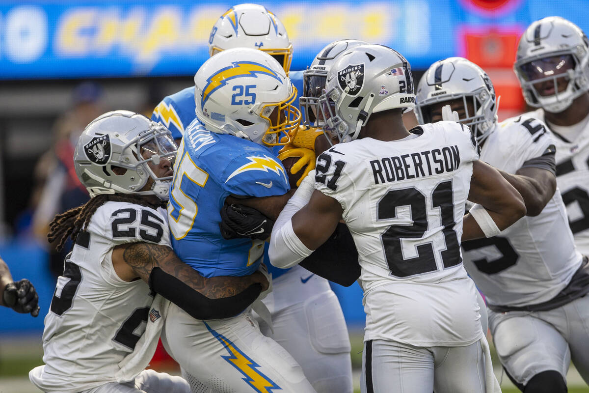 Los Angeles Chargers running back Joshua Kelley (25) is gang tackled by safety Tre'von Moehrig ...