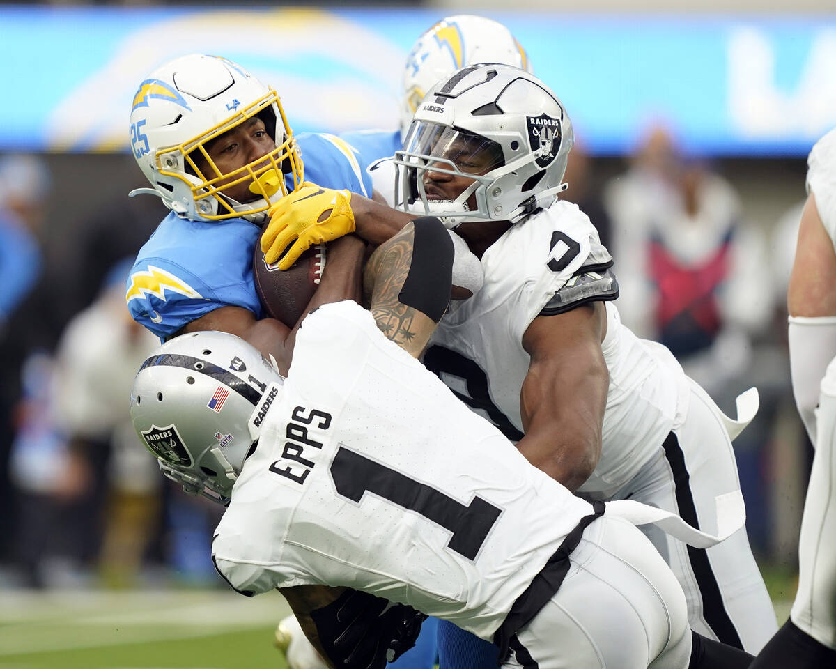 Los Angeles Chargers running back Joshua Kelley, left, is tackled by Las Vegas Raiders safety M ...