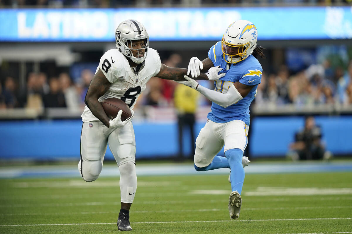Las Vegas Raiders running back Josh Jacobs runs next to Los Angeles Chargers cornerback Ja'Sir ...