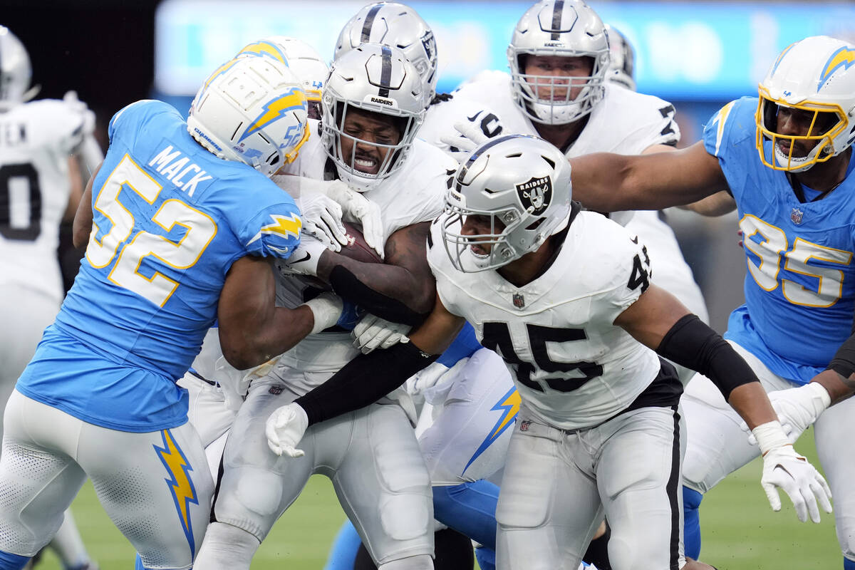 Las Vegas Raiders running back Josh Jacobs, center, is tackled by Los Angeles Chargers lineback ...