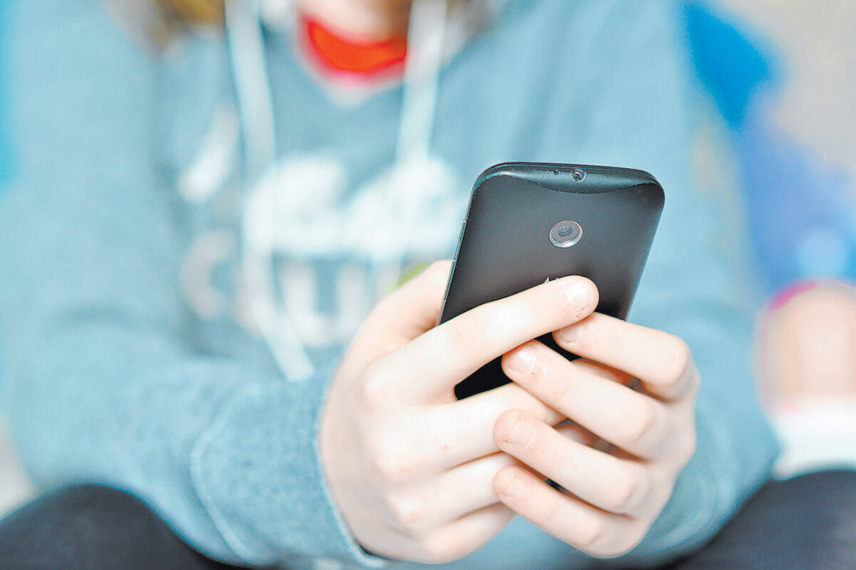 Teen holding mobile (cell) phone in hands.