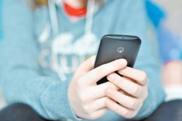 Teen holding mobile (cell) phone in hands.