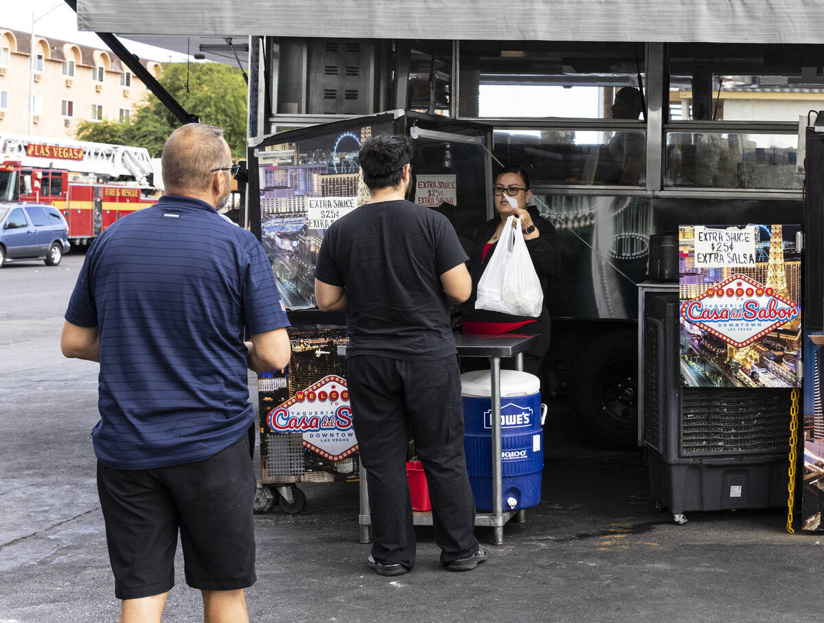 Customers wait in line to pick up their food from Casa del Sabor food truck at the corner of Bo ...