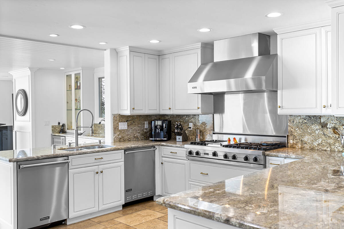 The chef’s kitchen features updated stainless-steel appliances, a double oven, granite counte ...