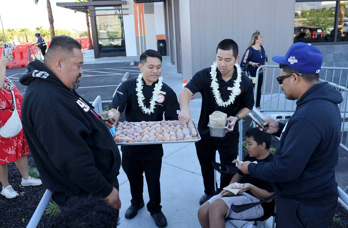 Cameron Ishikawa, left, and Everett Kim hand out malasadas to people waiting in line for the gr ...