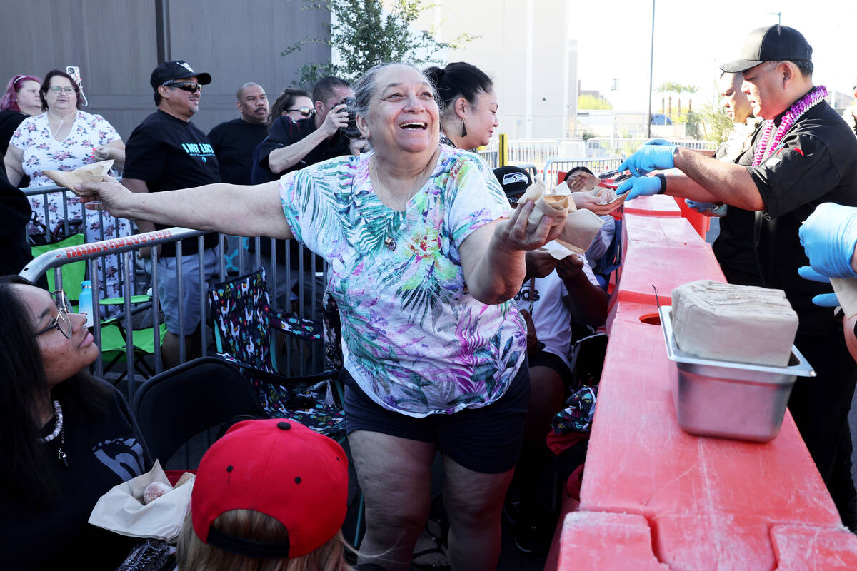 Bonnie Benarao of Las Vegas helps hand out malasadas near the front of the line for the grand o ...