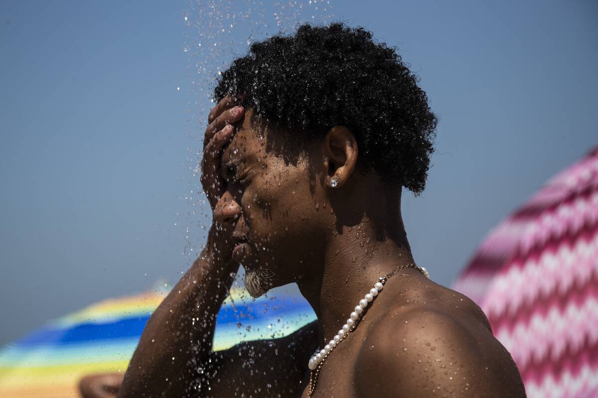 FILE - A man cools off in a shower at Ipanema beach, Rio de Janeiro, Brazil, Sept. 24, 2023. Af ...