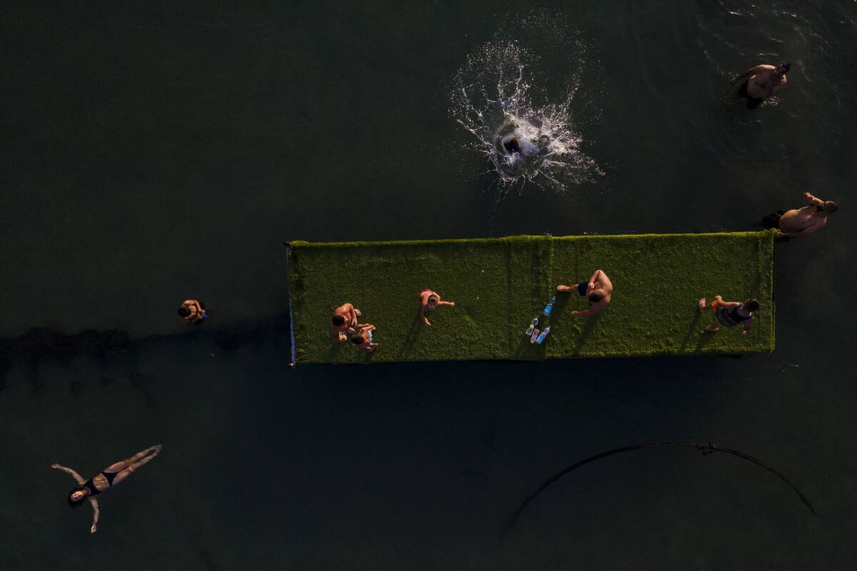 FILE - People cool off as they bate in the Mediterranean sea in the old port of Acre, north Isr ...