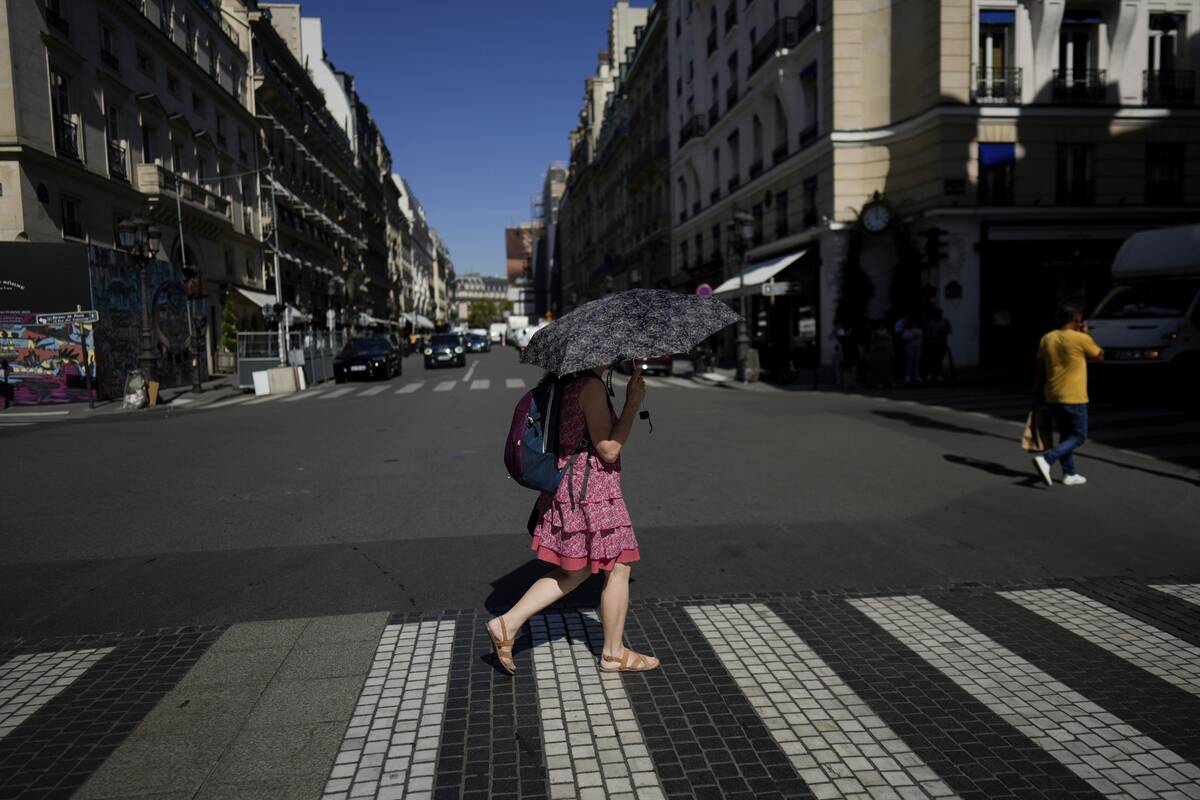 FILE - A woman holds an umbrella to protect herself from the sun, in Paris, Sept. 6, 2023. Afte ...