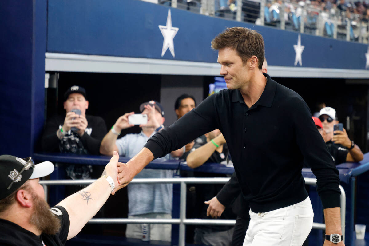 Former quarterback Tom Brady, right, greets fans as he walks off the field after players warm u ...