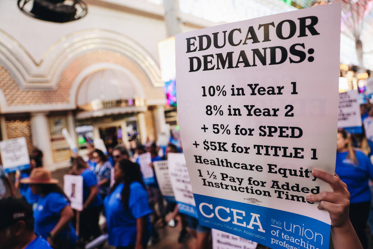 A demonstrator holds up a sign with demands listed from the Clark County Education Association ...