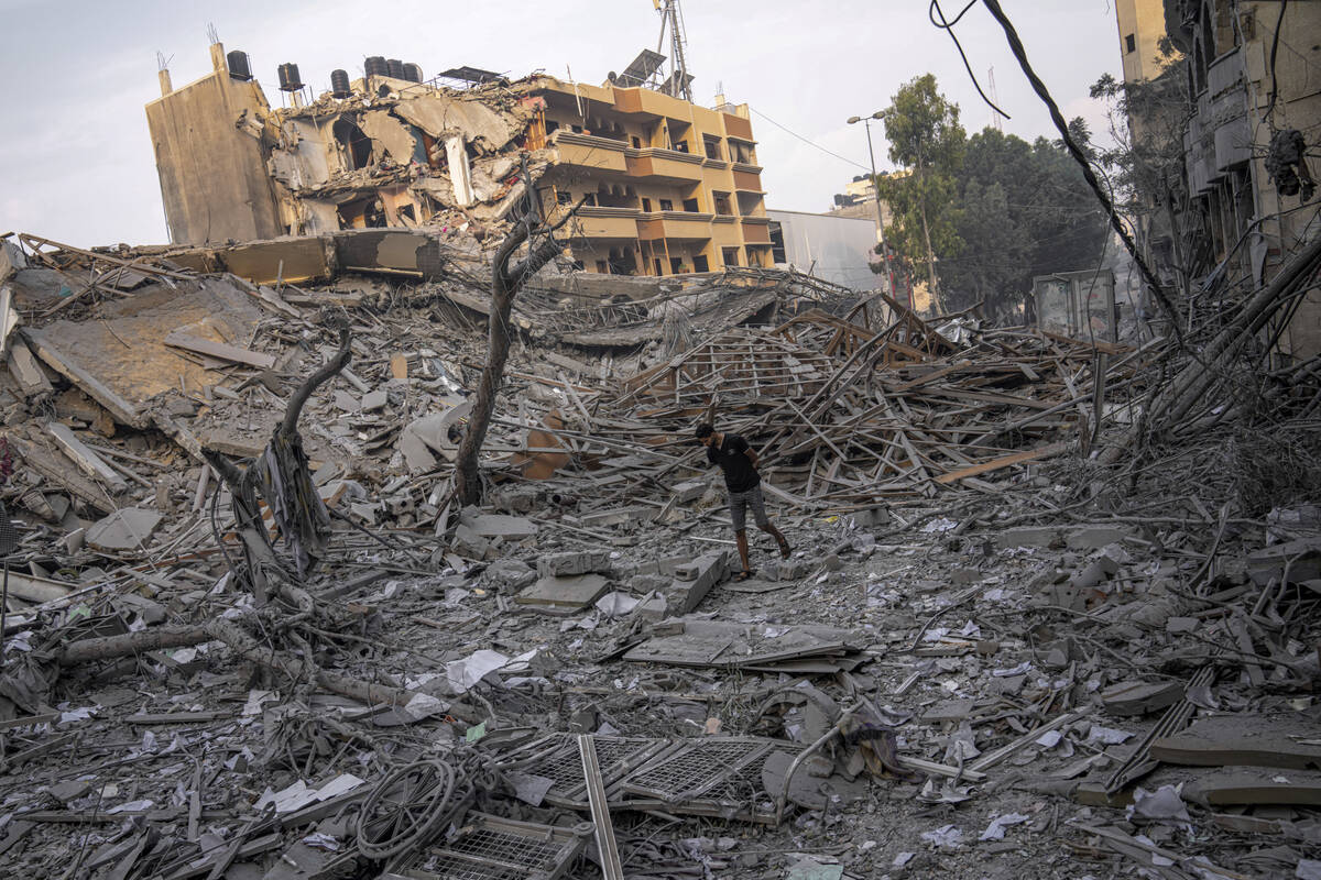 Palestinians inspect the rubble of a building after it was struck by an Israeli airstrike, in G ...