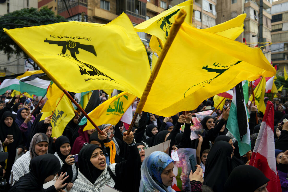 Hezbollah supporters wave the group's flag, as well as those of Palestinian and Lebanon during ...