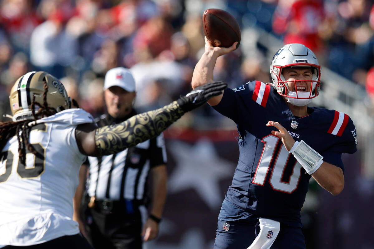 New England Patriots quarterback Mac Jones (10) looks to pass the ball while under pressure fro ...