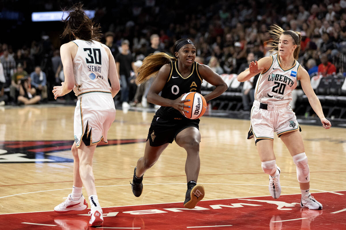 Las Vegas Aces guard Jackie Young (0) drives between New York Liberty forward Breanna Stewart ( ...