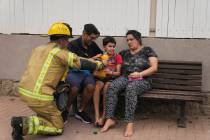 An Israeli firefighter hands a drink to a young child next to a site struck by a rocket fired f ...