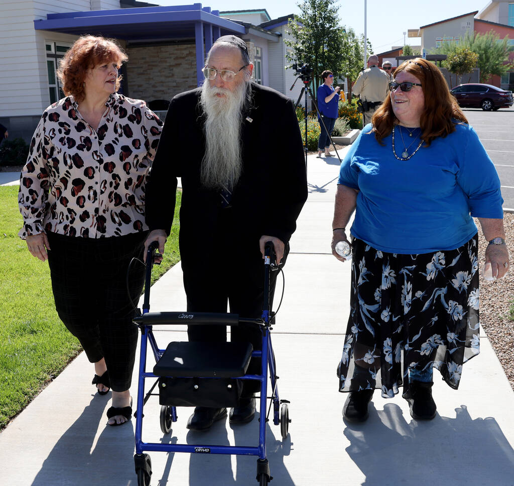 Hal Goldblatt, center, who is still recovering after being hit by a car a year ago, walks with ...