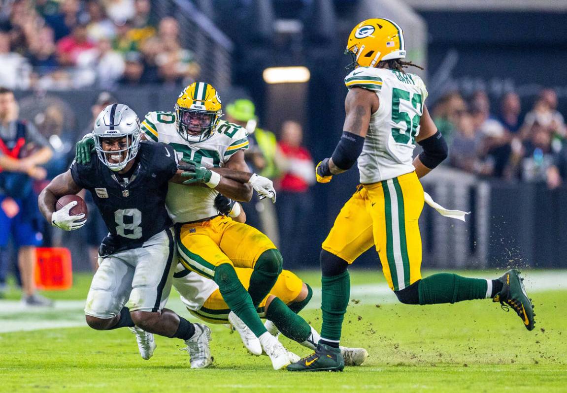 Raiders running back Josh Jacobs (8) is pulled down by Green Bay Packers safety Rudy Ford (20) ...