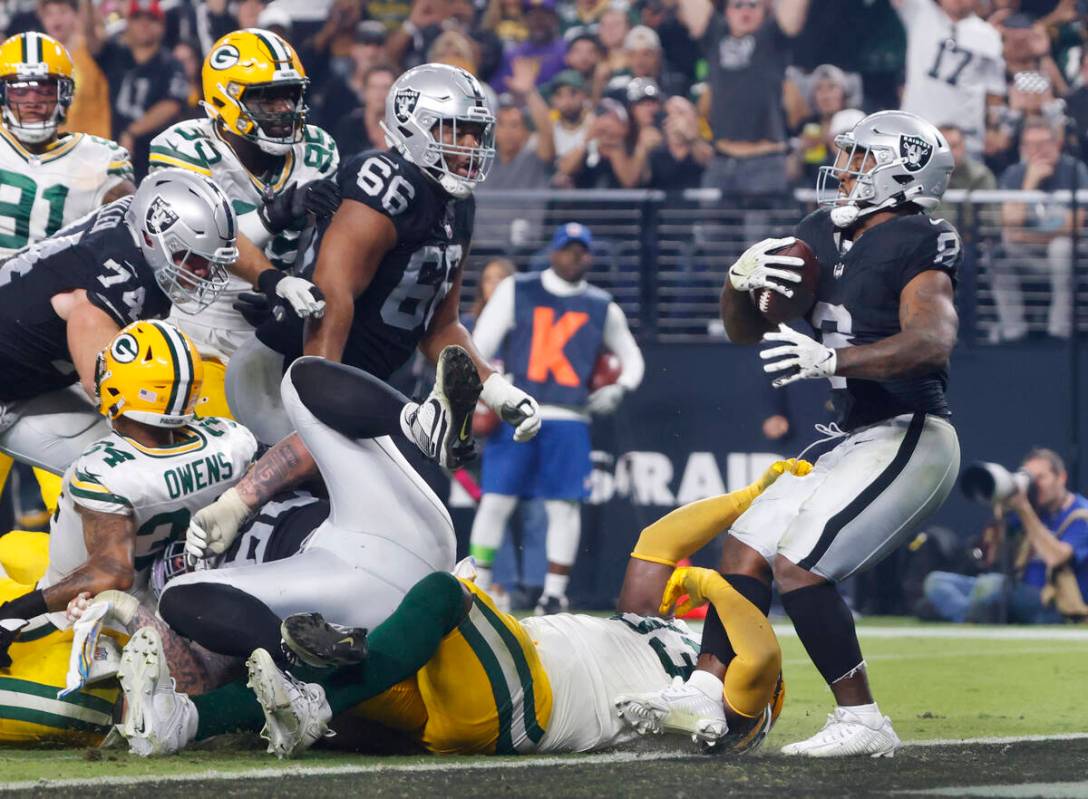 Raiders running back Josh Jacobs (8) breaks through tackles by the Green Bay Packers defensive ...
